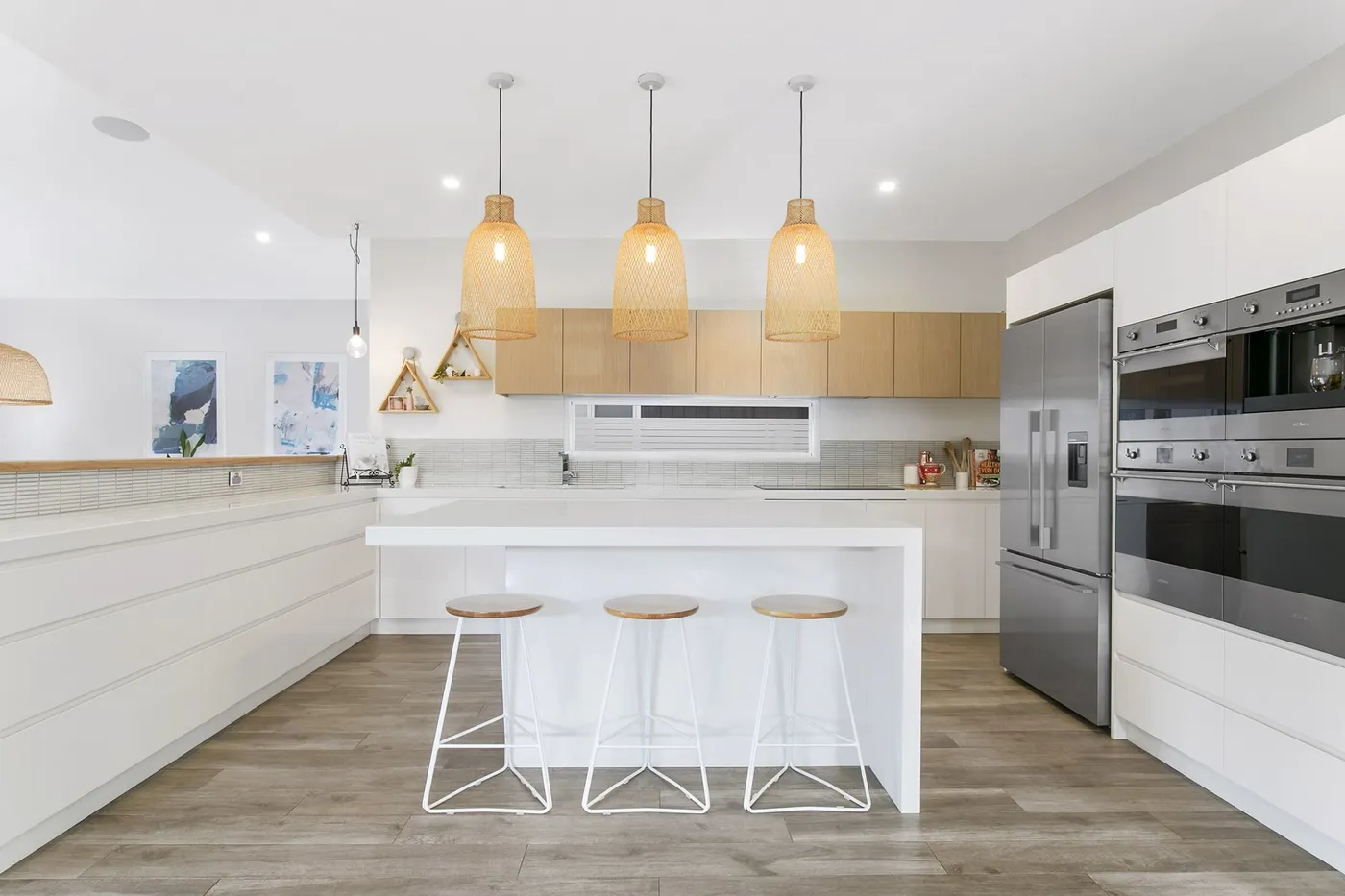 A white kitchen with island bench and timber floors